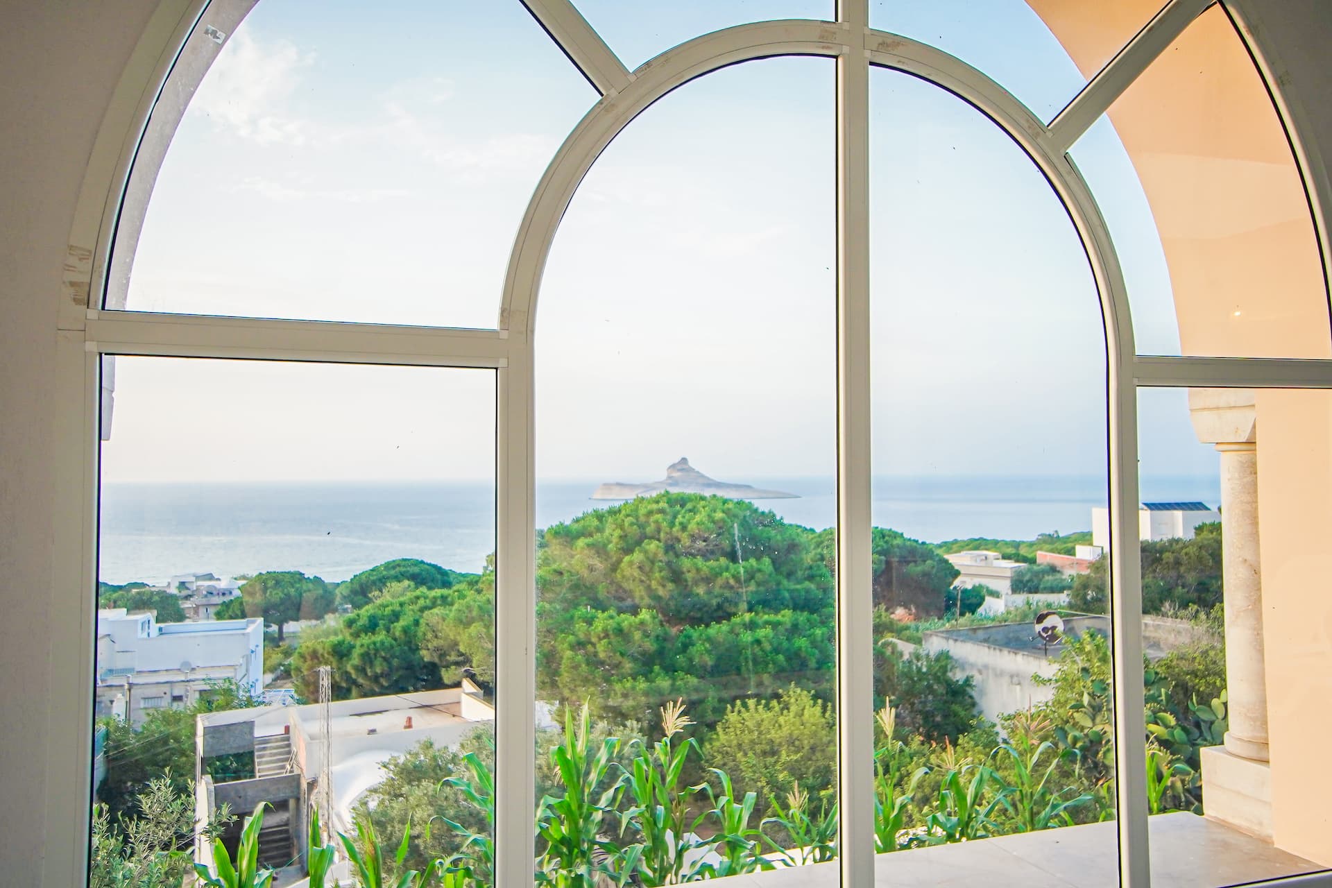 Vue sur la mer et l'île de Pilau à travers une baie vitrée en arcades